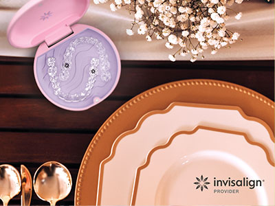 The image features a collection of tableware, including plates and serving dishes, displayed on a wooden surface with a pink box containing dental products in the background.