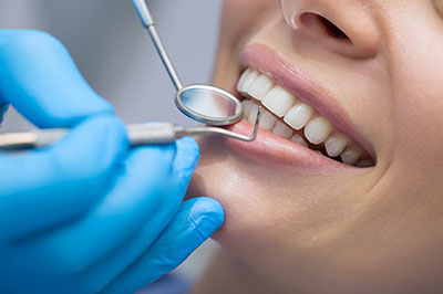 The image depicts a dental professional performing oral care on a patient, with the focus on the dental instruments and the patient s smile.